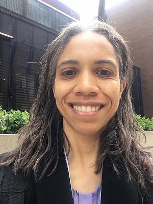 Portrait photo of a Black woman with shoulder length dark hair, smiling for the camera.